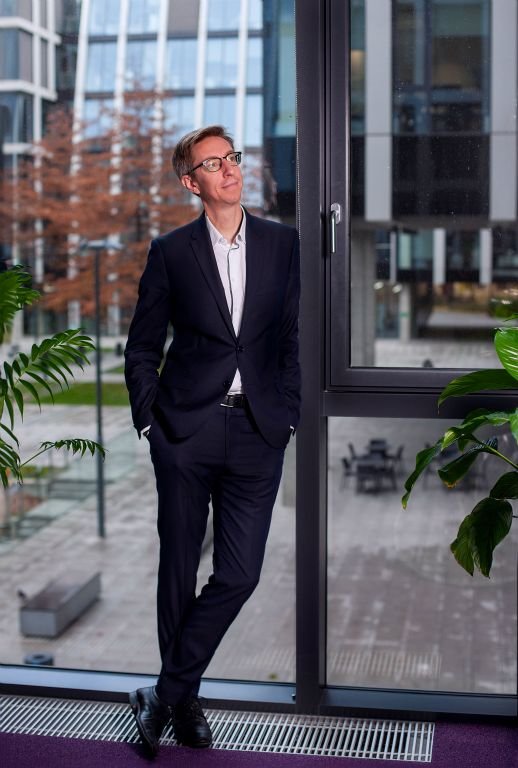 Full-length portrait of a man in a suit by the windows