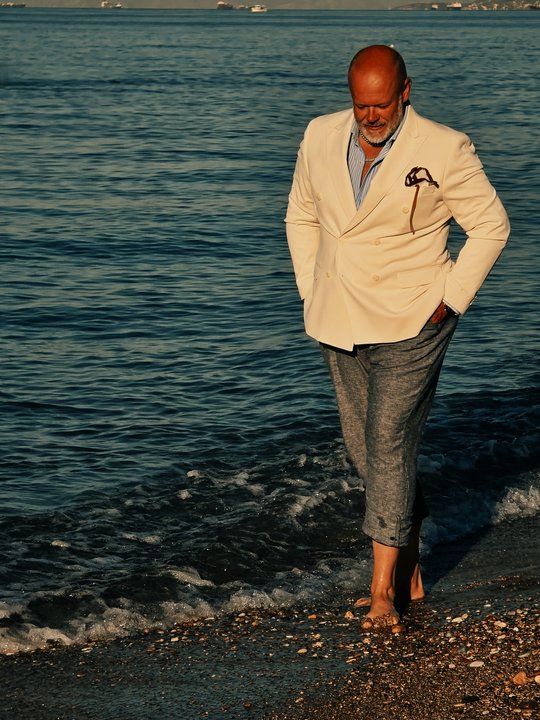 Petr Lukeš wearing a light jacket and relaxed trousers by the sea